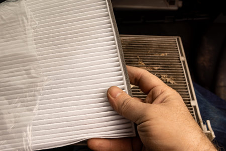 A clean new cabin air filter held above a very dirty old one, showing how much better your car's air...