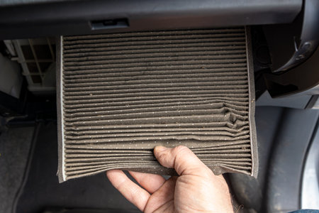 Hand holding dirty cabin air filter, representing invisible accumulation of pollutants inside vehicles and importance of regular inspection to maintain a healthy driving environment, selective focusの写真素材