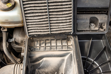 A heavily contaminated engine air filter removed from the intake housing, showing accumulated dust, debris, and fibers indicating poor airflow and the need for replacement with selective focusの写真素材