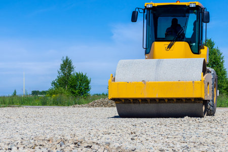 Heavy compaction equipment rolling over crushed stone to create stable subgrade for pavement or...