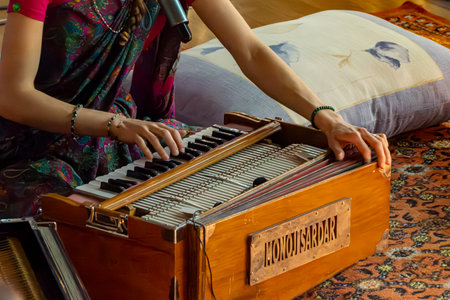 Russia, Kemerovo - February 15, 2025. Cultural tradition causes use of harmonium for chanting or prayer. Wooden instrument and sari result from regional aesthetic preferences. selective focusのeditorial素材