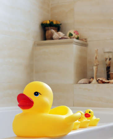 Yellow toy ducks for bathing small children standing on the edge of the white bathtubの写真素材