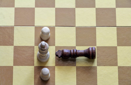The king's chess piece lying in front of the white pieces on the chessboard