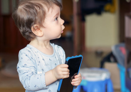 One-year-old boy holding a blue mobile phone in his hands