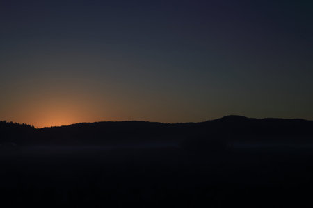The glow of the sun rising from behind the hills somewhere in Poland