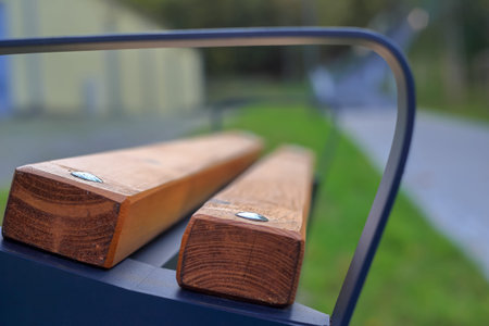 A brown wooden bench with a metal railing against a blurry background in Poland