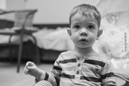 Black and white portrait of a sitting two year old boy at homeの写真素材