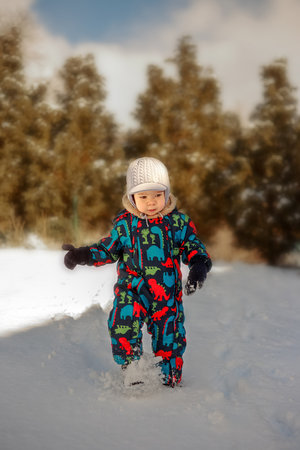 A little boy in a winter suit running down a hill in the snow in Polandの写真素材