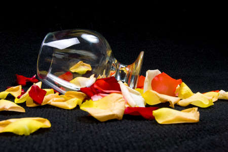 Empty Cognac Glass and Roses Petals on Blackの写真素材