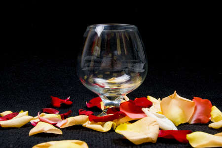Empty Cognac Glass and Roses Petals on Blackの写真素材
