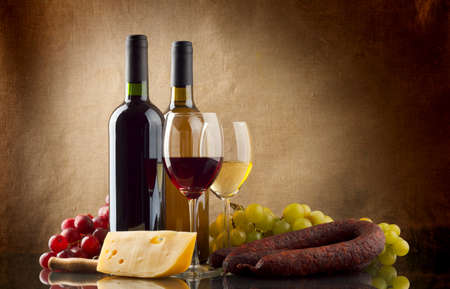 Wine in bottles and glasses, grapes, cheese an sausage on linen backgroundの写真素材