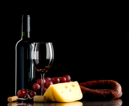 Wine in bottle and glass, grapes, cheese an sausage on black backgroundの写真素材