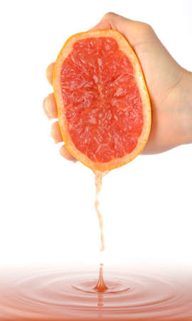 Hand squeezing a grapefruit to a large amount of juiceの写真素材