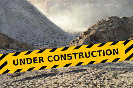 Image of dusty building site during working with under construction yellow tape