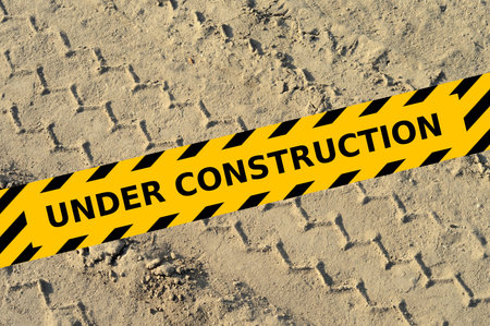 Truck tire track in a sand at building site with under construction yellow tapeの写真素材