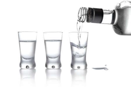 Close-up view of bottle and glasses of vodka poured into a glass isolated on whiteの写真素材