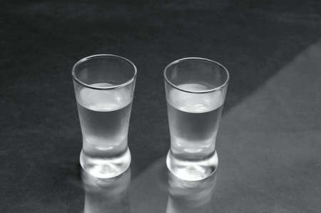 Close-up view of two glasses of vodka on black marble tableの写真素材