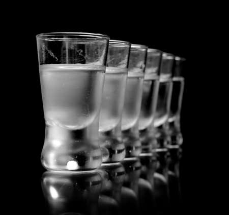 Close-up view of many glasses of vodka standing isolated on blackの写真素材