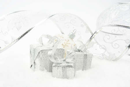 Decoration of silver christmas gifts with ribbon on snow on white backgroundの写真素材