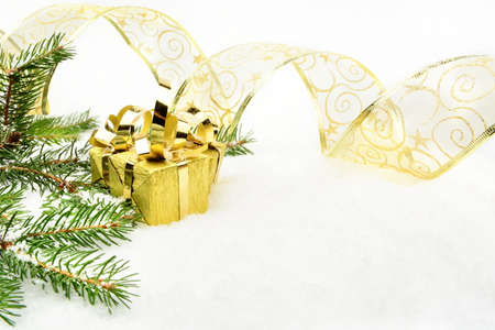 Decoration of gold christmas gifts, gold ribbon on snow christmas tree branch on whiteの写真素材