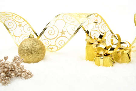 Decoration of golden christmas gifts,baubles,ribbon on snow on whiteの写真素材