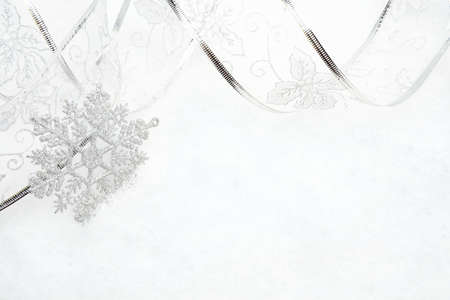 Decoration of silver christmas snowflake with ribbon on snowの写真素材