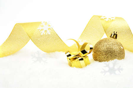 Decoration of golden christmas gift with ribbon on snow on white backgroundの写真素材
