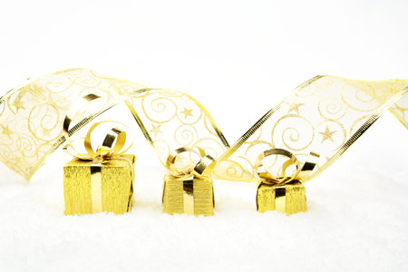 Decoration of golden christmas gifts with ribbon on snow on white background