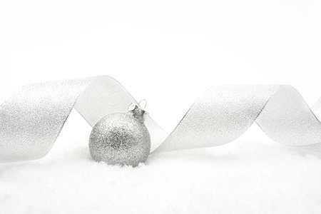 Decoration of Silver glitter bauble with ribbon on snow on white background