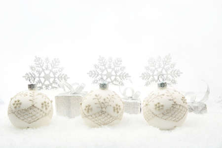 Decoration of silver christmas gifts and baubles and snowflakes on snow on white backgroundの写真素材