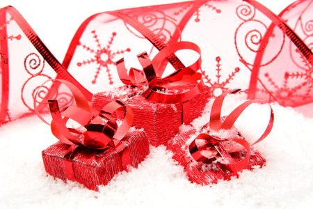 Decoration of red christmas gifts with ribbon on snow on white background