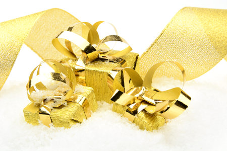 Decoration of golden christmas gifts with ribbon on snow on white backgroundの写真素材