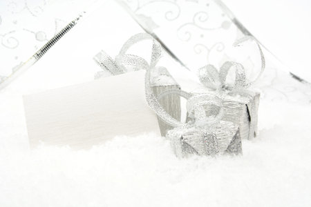Silver christmas decoration, gifts with ribbon with wishes card on snow white background