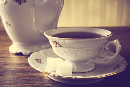 Old-fashioned porcelain jug with a cup of coffee with old-styled wallpaper backgroundの写真素材
