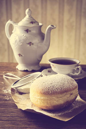 loseup shot of doughnut with cup of tea with old-fashioned wallpaper with strainerの写真素材