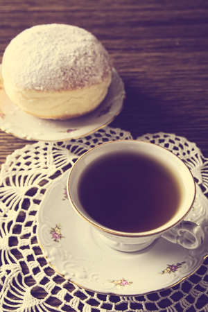 Donut with cup of tea on napkin with old-fashioned wallpaperの写真素材