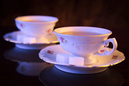 Old-style image with two porcelain cups of tea on black backgroundの写真素材