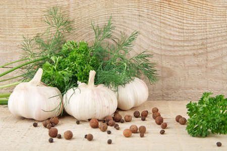 Dill leaves,garlic,pepper and allspice on rural wooden boarding backgroundの写真素材