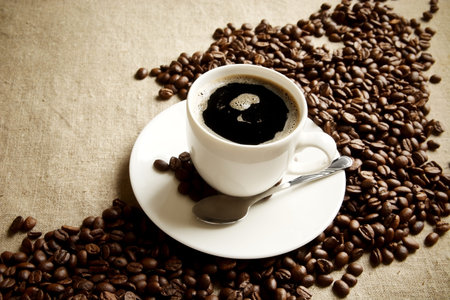 Wave made of coffee beans with cup of coffee with foam on linen,flax