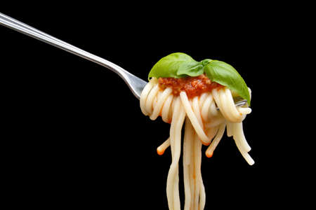 Pasta wound on fork with basil leaf on black backgroundの写真素材