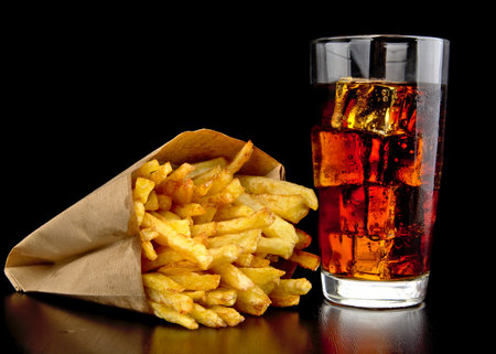 Big single cheeseburger with french fries on black wooden desk