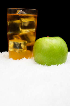 Apple juice,ice cubes and whole apple on black background on snowの写真素材