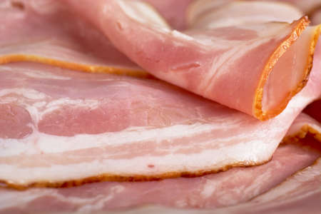 Assorted slices of fat pink bacon backgroundの写真素材