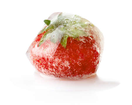 Strawberry fruit frozen in ice cube isolated on white backgroundの写真素材