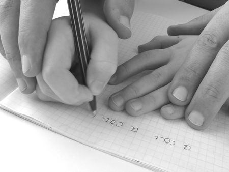 close-up photo of the hands of girl and her father during training to writeの写真素材