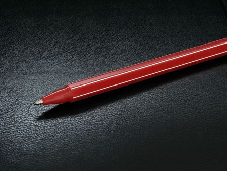 red ballpoint pen at the black leather background                               の写真素材