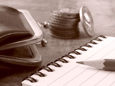 sepia toned notepad with pencil and purse with coins stack                               の写真素材