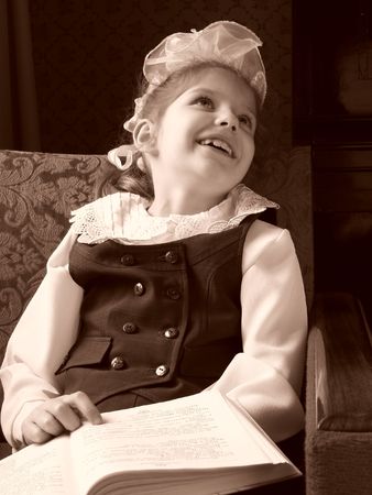 sepia toned smiling schoolgirl with big bow and open bookの写真素材