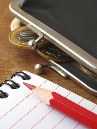 shallow DOF red pencil with notepad and purse with coins                               