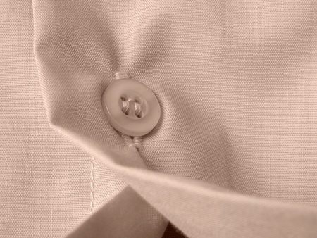 sepia toned shirt fragment with button closeup                               